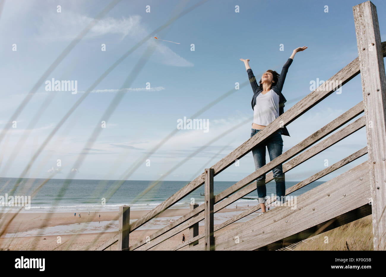 Happy woman standing on boardwalk at the beach with raised arms Stock ...