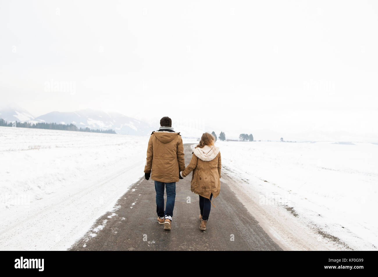 Back view of young couple in love walking hand in hand on country road ...
