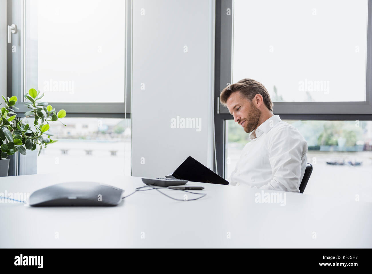 Businessman sitting at desk of his office looking at documents Stock Photo