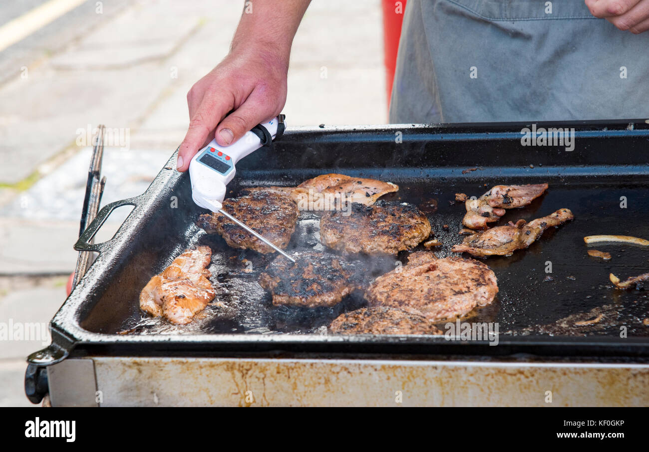 A man measuring the temperature in a beef burger on a market stall, St Davids, Haverfordwest, Pembrokeshire, South Wales. Stock Photo
