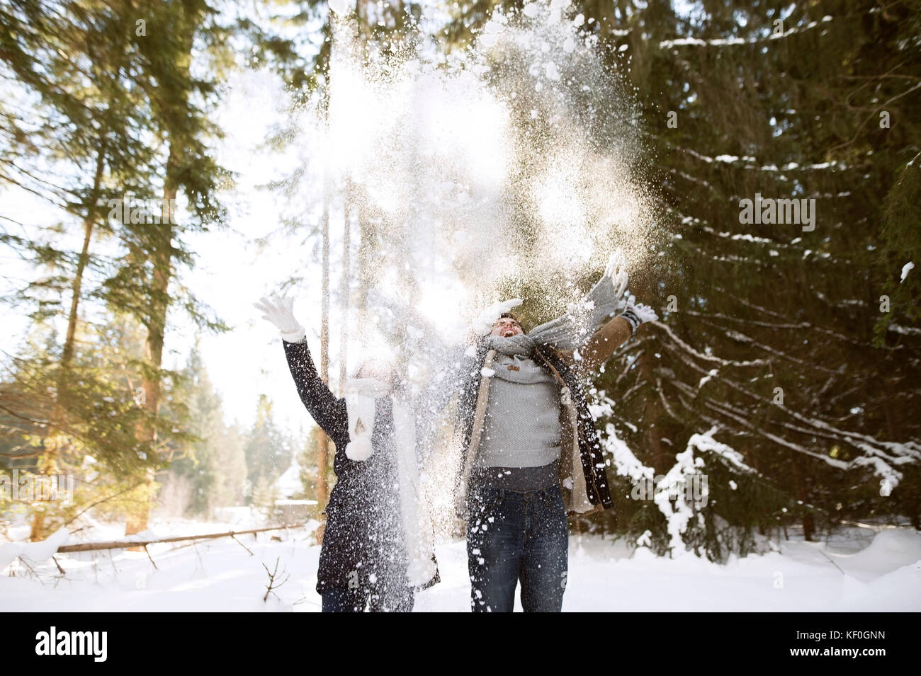 Happy young couple throwing snow in the air in the forest Stock Photo ...