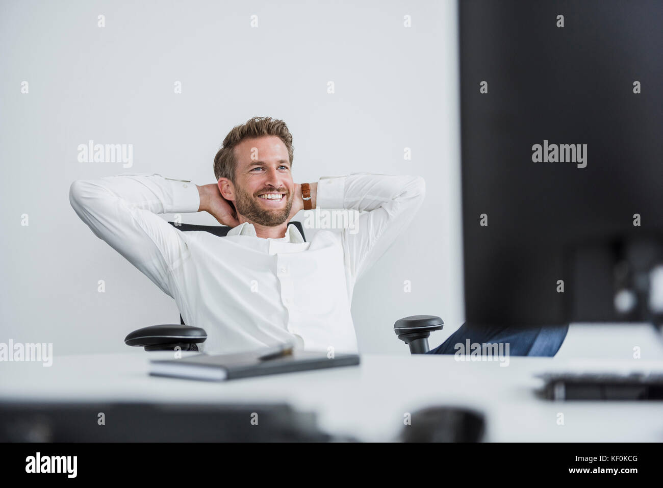 Portrait of content businessman relaxing at desk in his office Stock Photo