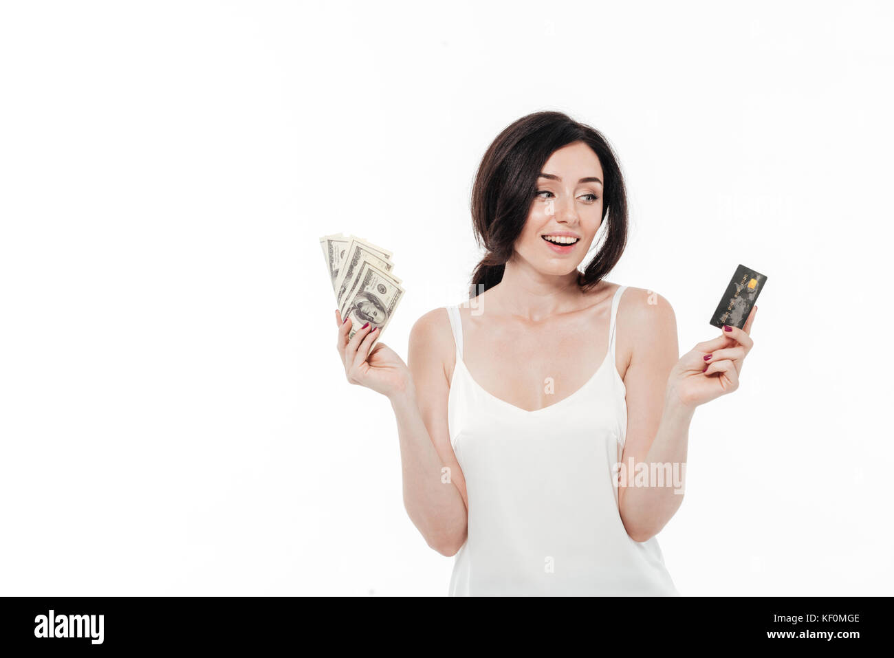 Portrait of a happy young woman choosing between bunch of money banknotes and a credit card isolated over white background Stock Photo