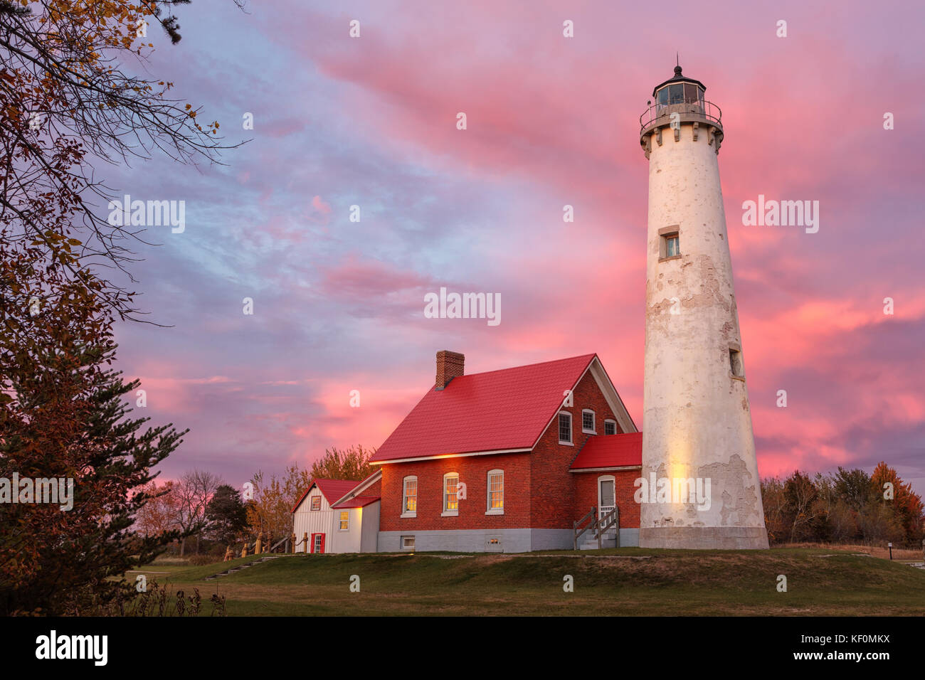 Tawas Point Lighthouse at Sunset in Tawas Michigan. A vivid sunset paints the sky at twilight, behind the lighthouse at Tawas Point State Park. A glow Stock Photo