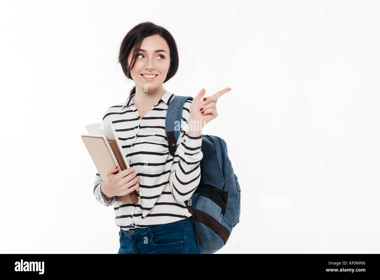 Portrait of a smiling teenage girl with backpack holding books while ...