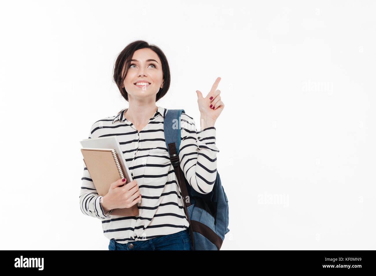 Portrait of a happy teenage girl with backpack holding books while ...