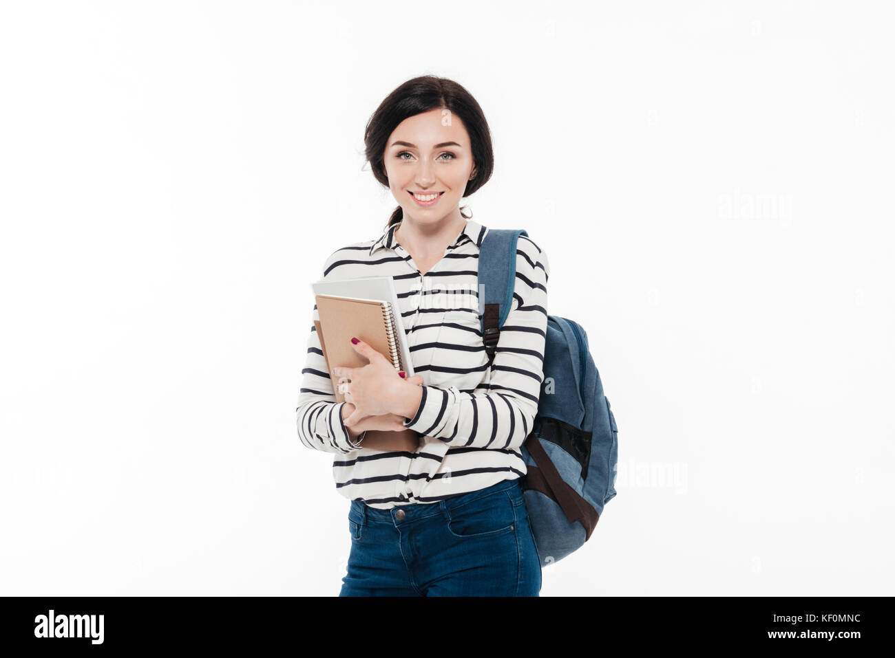 Portrait of a cheerful teenage girl with backpack holding books while ...