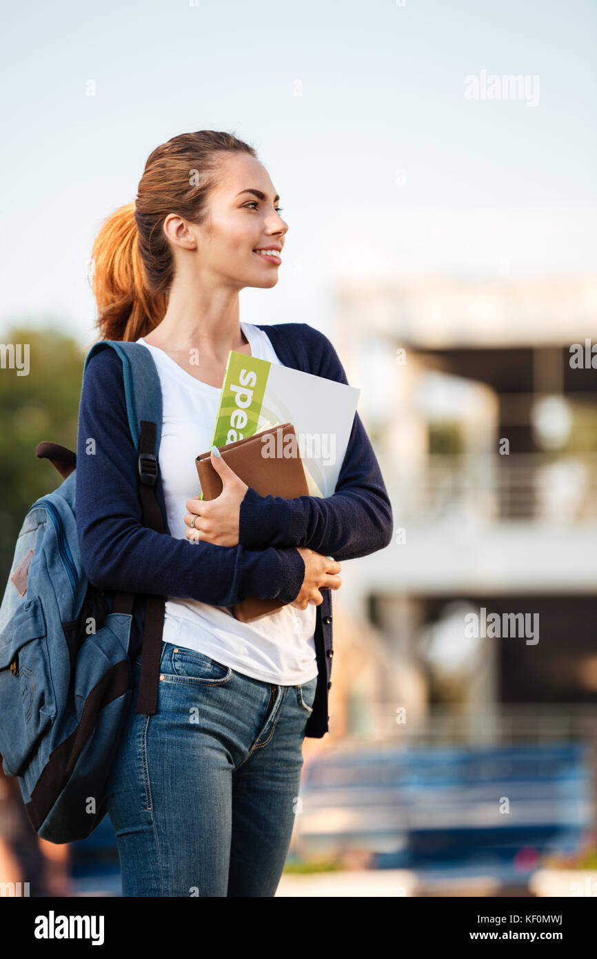 Portrait of a young pretty student girl standing with backpack and ...