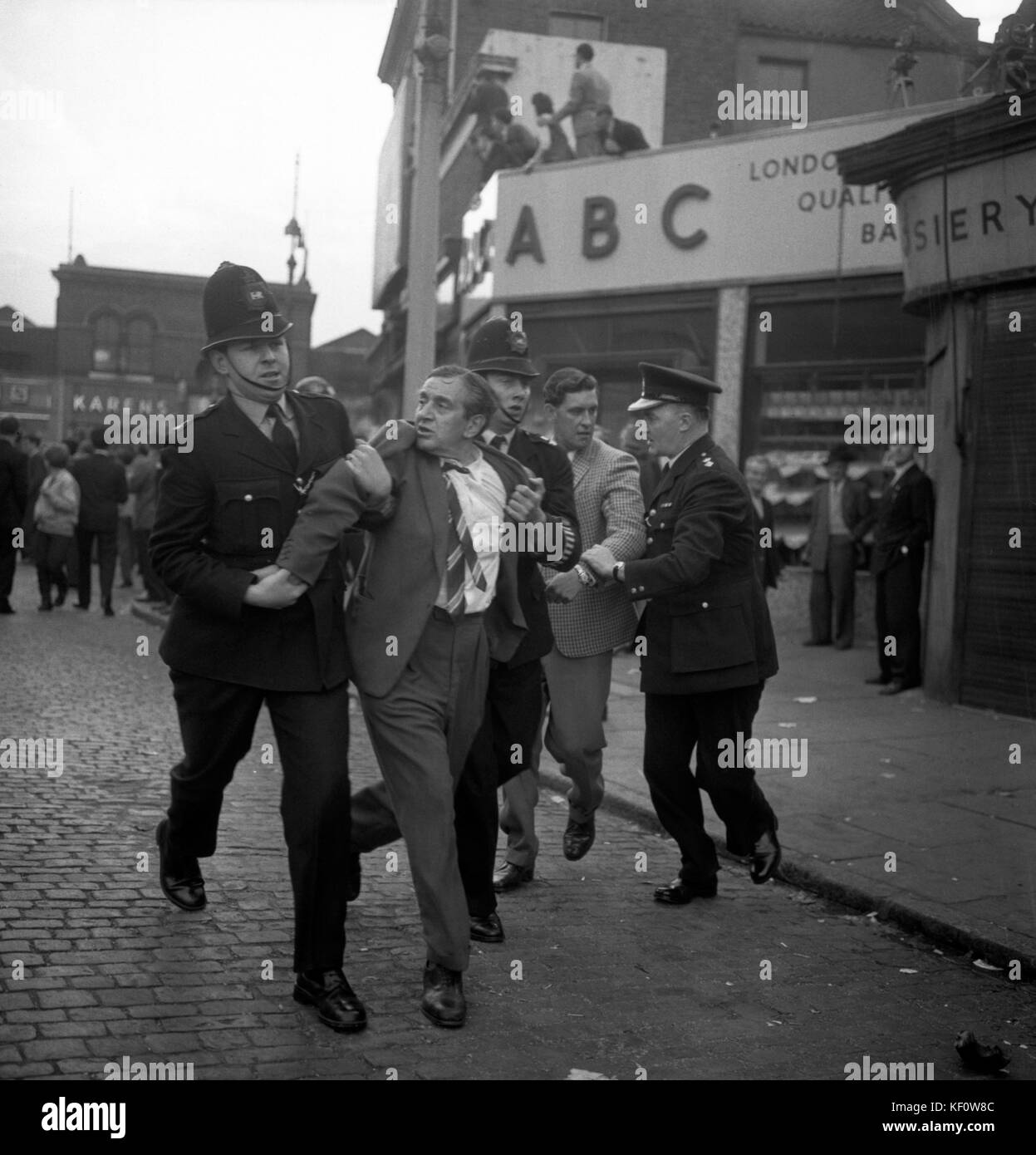 Two men are hustled away in the grip of police at the stormy meeting of Sir Oswald Mosley's Union Movement at Ridley Road, Dalston, London. With a strong police presence controlling the crowd, Sir Oswald attempted to address the meeting amid shouts and boos. There were scuffles and a number of arrests were made. Sir Oswald ended the meeting on police advice. Stock Photo