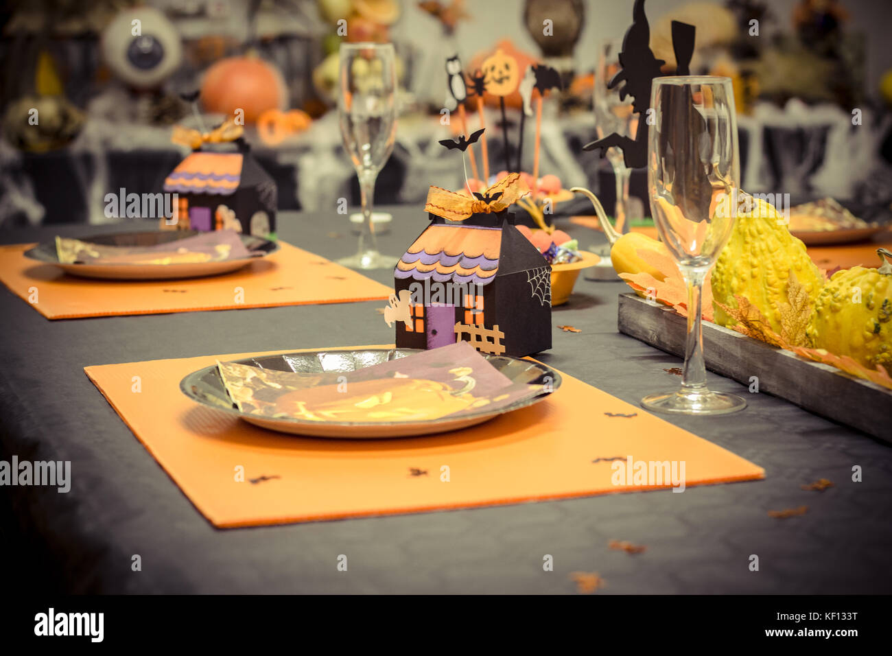 Reception table with a black tablecloth and decorations for halloween party, a small cardboard house, glasses and plates in cartons Stock Photo