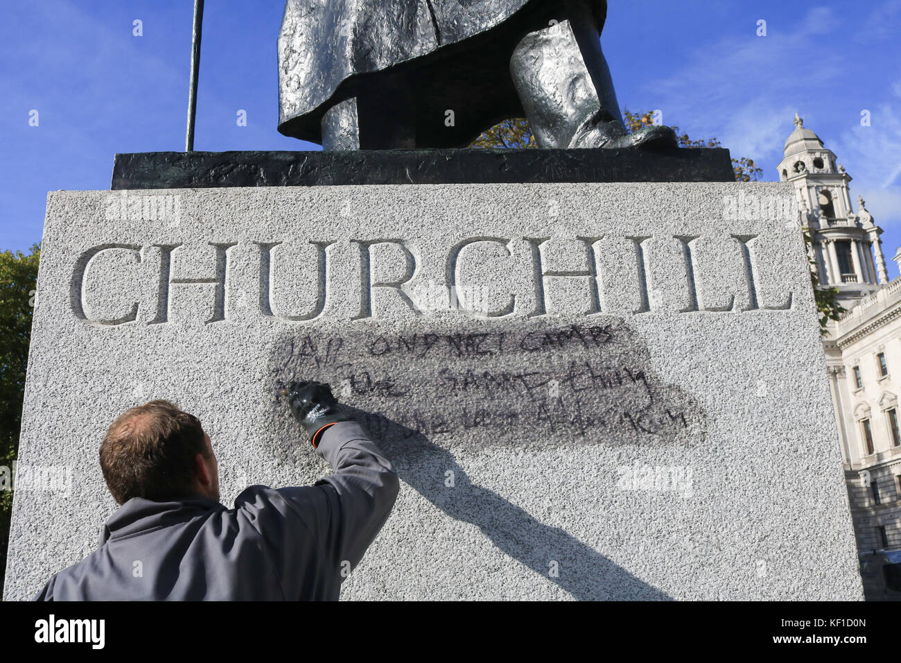 London, UK. 25th Oct, 2017. Westminster council Anti Graffiti unit wash and clean the Graffiti with the writing  still legible  ''Jail and Nazi camps are the same thing'  on the statue of Sir Winston Churchill opposite the Palace of Westminster left by Calais Jungle protesters the previous day. Credit: amer ghazzal/Alamy Live News Stock Photo