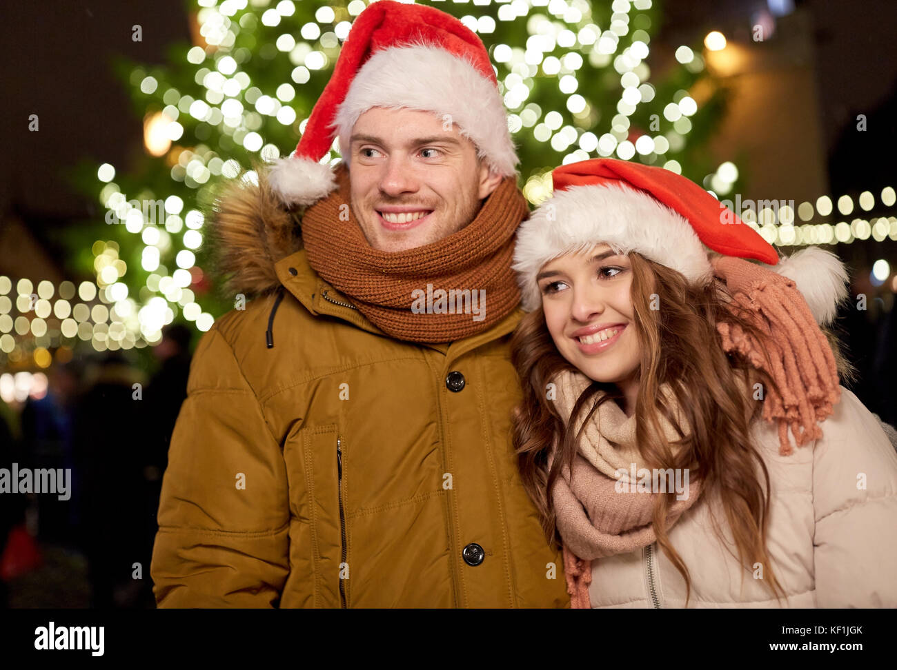 happy couple in santa hats at christmas tree Stock Photo - Alamy
