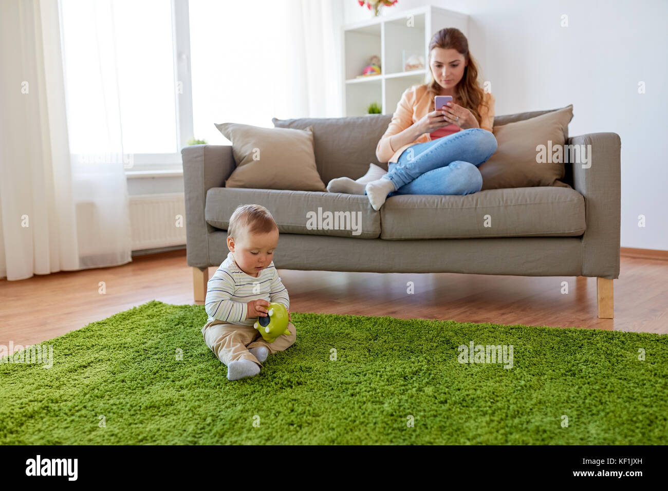 mother with smartphone and baby playing at home Stock Photo