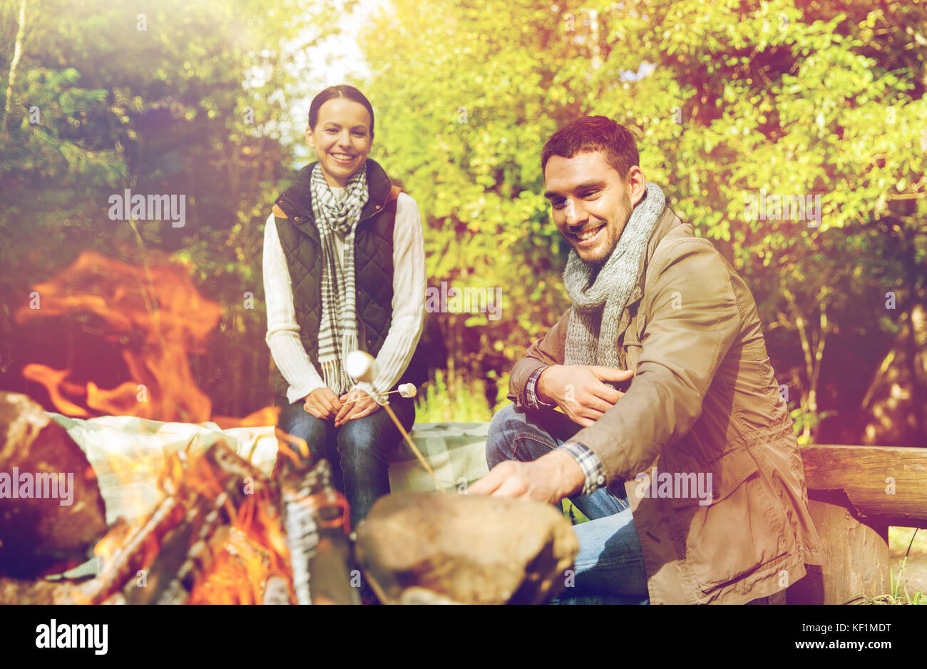 happy couple roasting marshmallow over camp fire Stock Photo