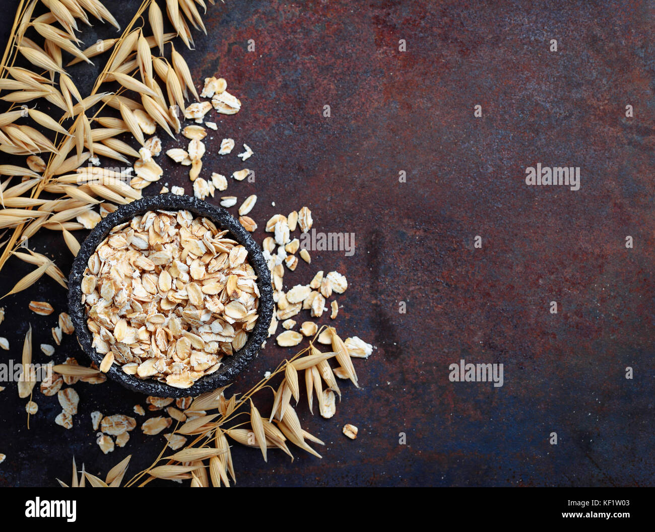 Oat flakes and spikelets on rusty background Stock Photo