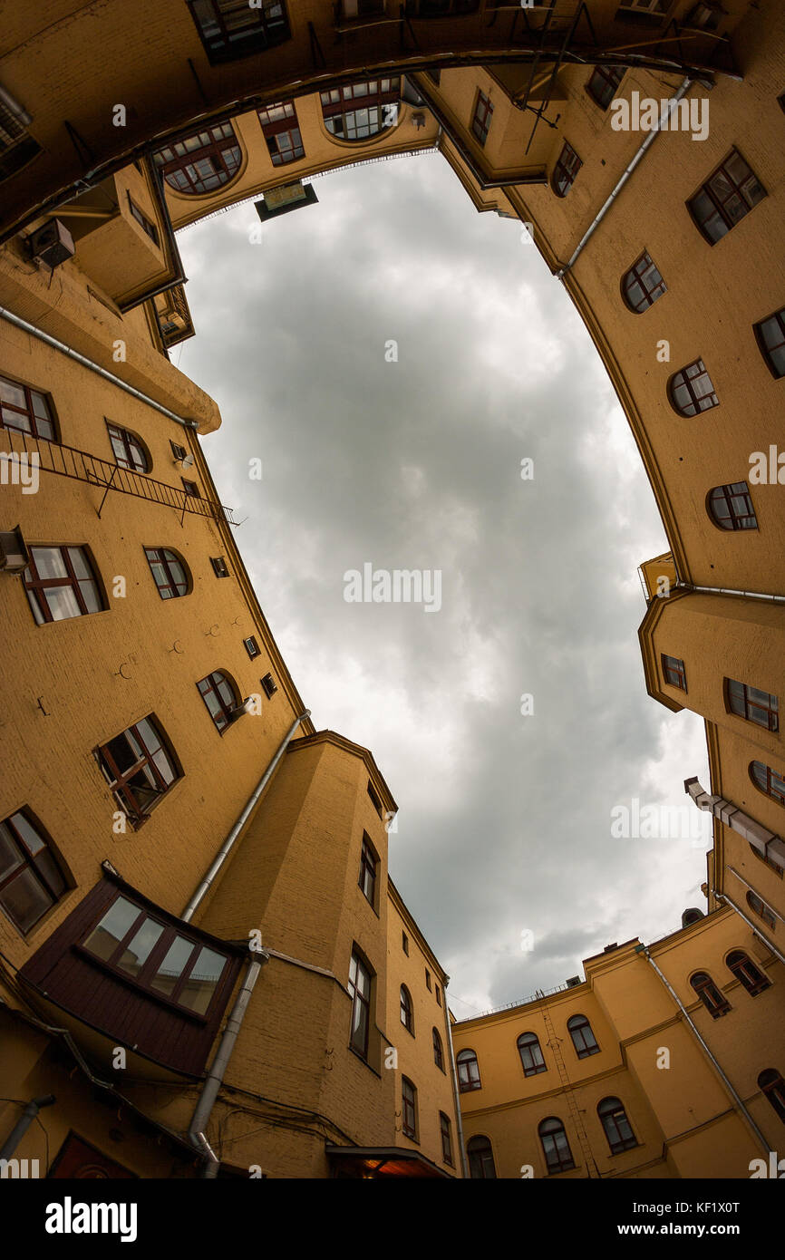 View on the old architecture buildings and cloudy sky from the ground. Walls form a frame for the sky. Stock Photo