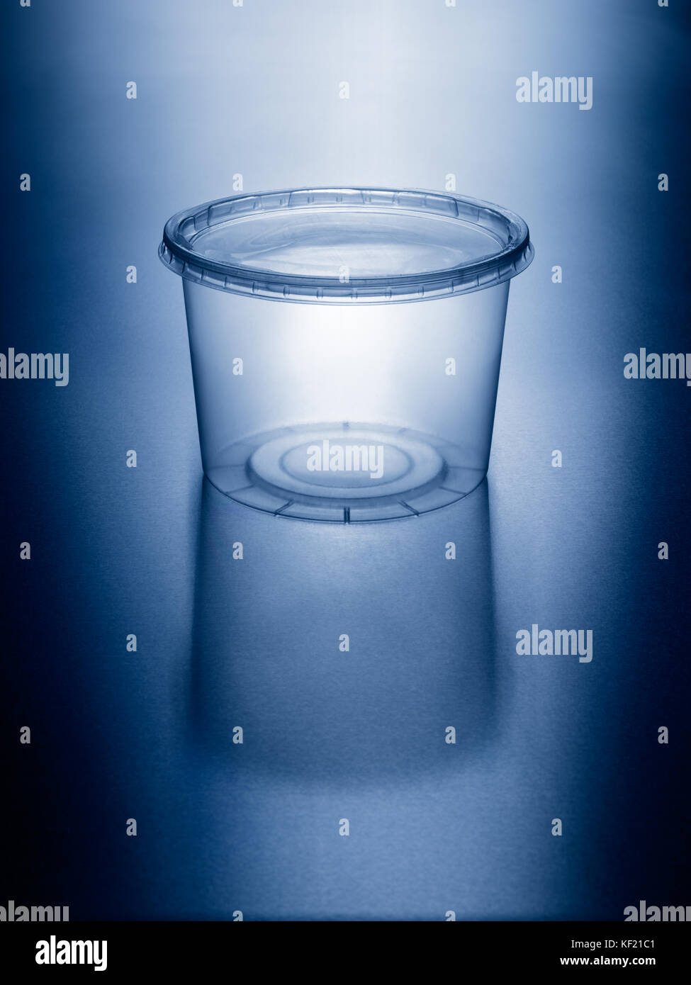 Light glowing through empty plastic food storage leftover container on reflective metal surface