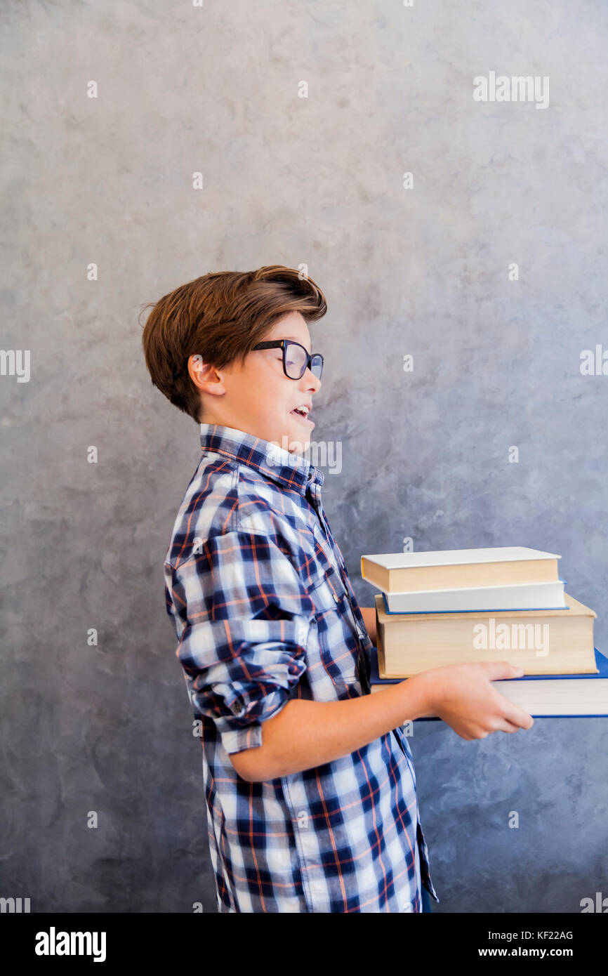 Cute teenage school boy holding books against wall Stock Photo - Alamy