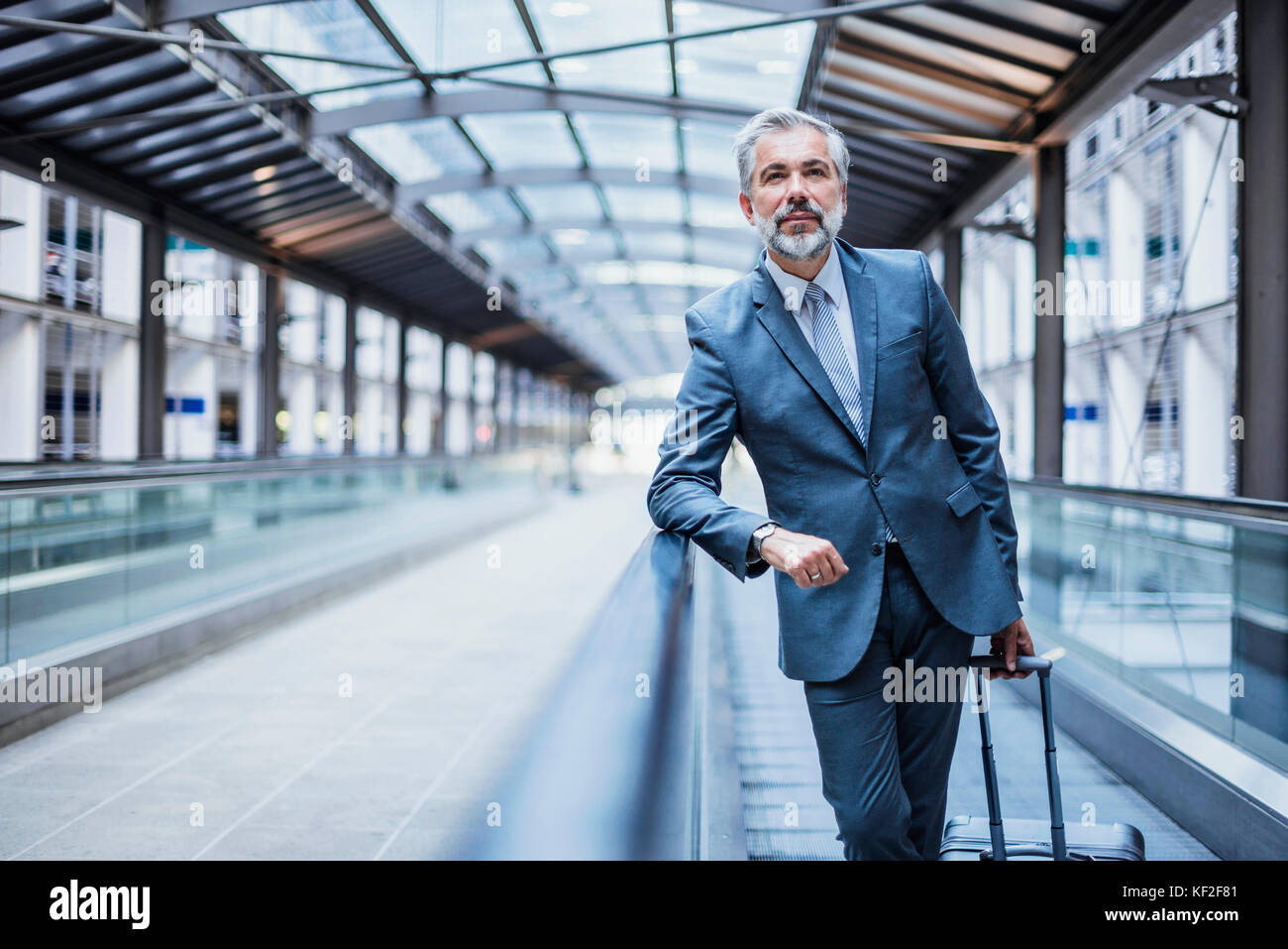 Businessman with luggage on moving walkway