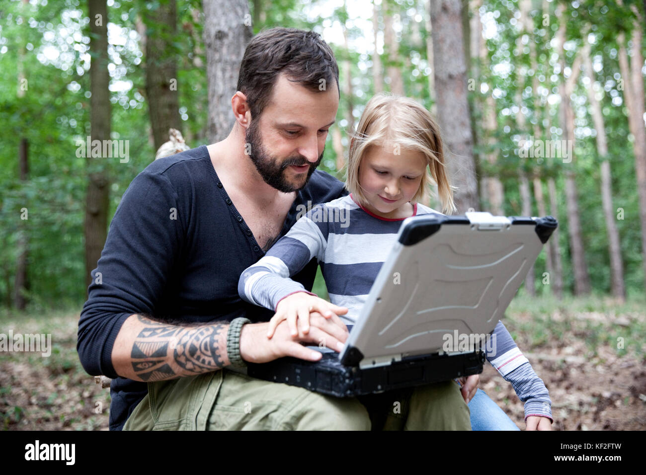 Father and daughter in forest using laptop Stock Photo - Alamy