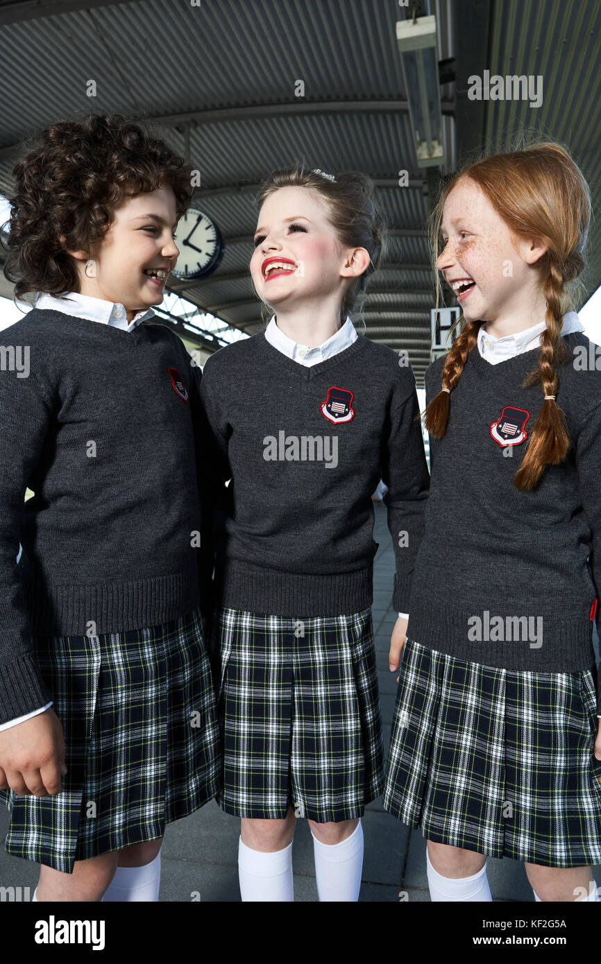 Three girls wearing school uniform talking on platform Stock Photo