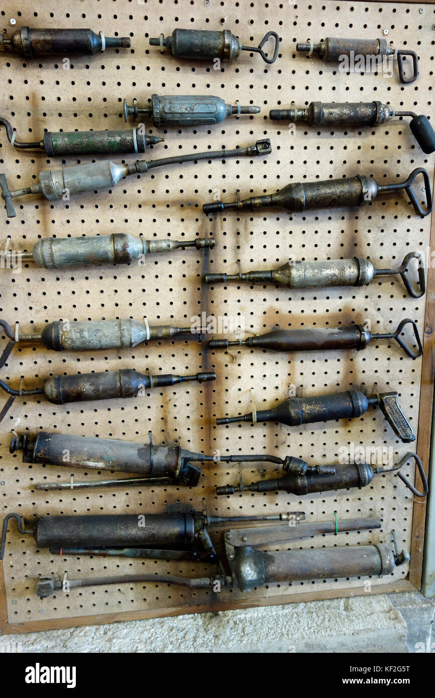 A display of antique grease guns on a wall Stock Photo