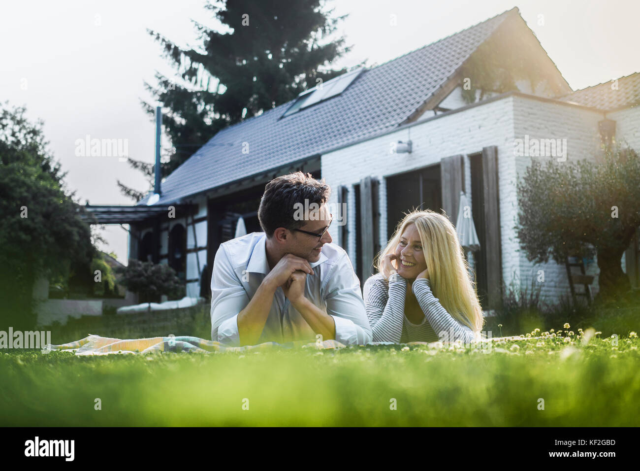 Happy mature couple lying on meadow in front of their house Stock Photo ...