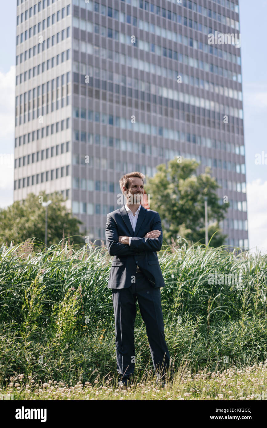 Smiling businessman standing on field in front of office building Stock ...