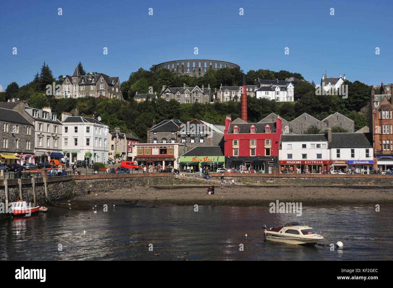 View of the resort town of Oban in Argyll in Scotland's West Highlands across the harbour showing the shops, restaurants, distillery & McCaig's Tower Stock Photo