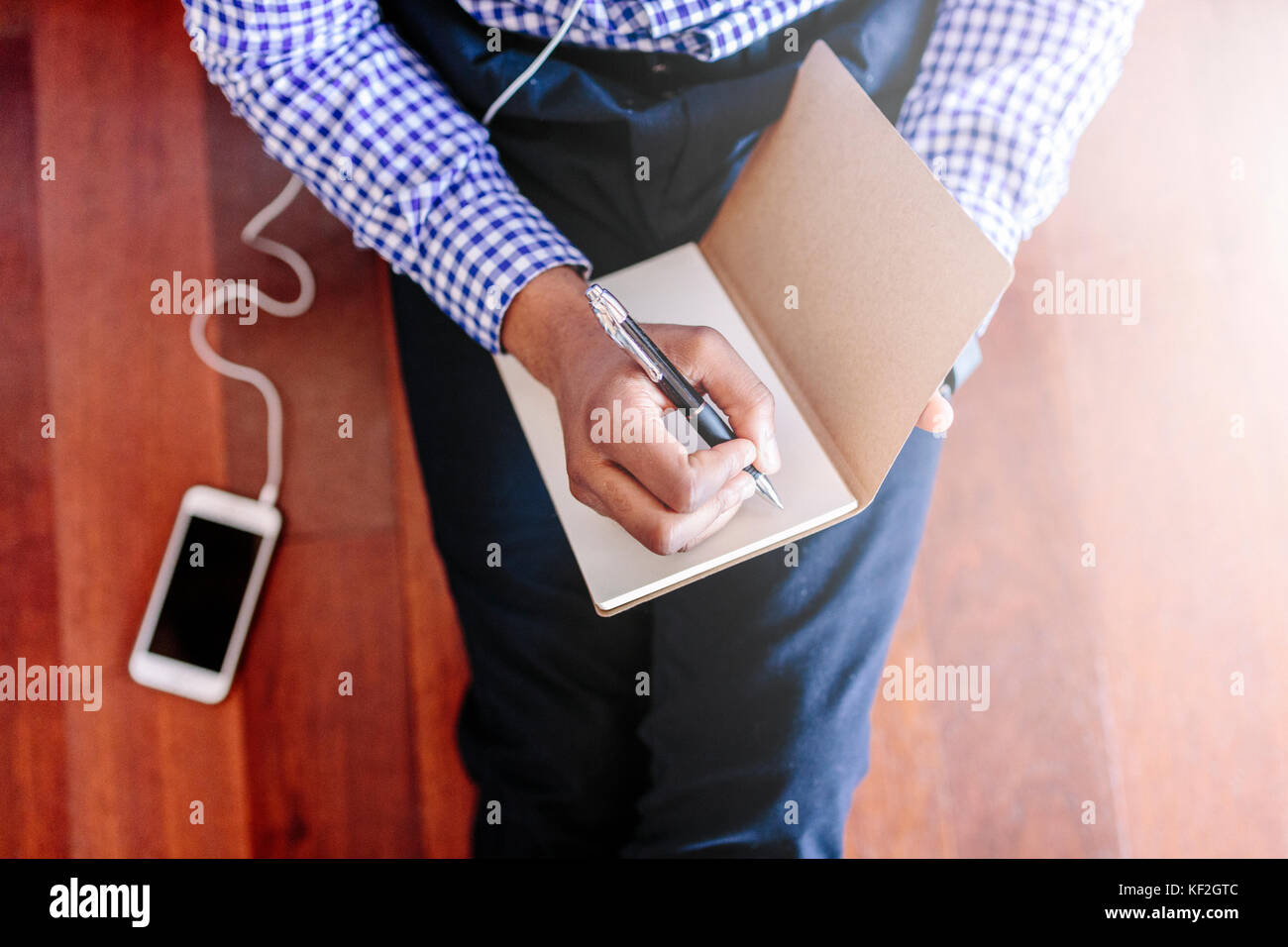 Man sitting on the wooden floor writing a note Stock Photo - Alamy