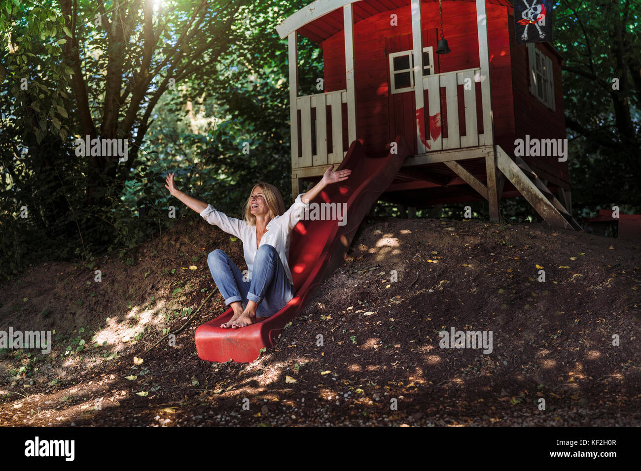 Mature woman sitting on slide in front of garden shed in the woods Stock  Photo - Alamy