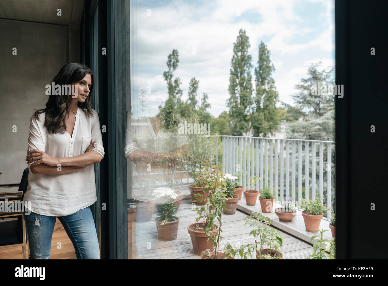 Woman at home looking out of window Stock Photo - Alamy