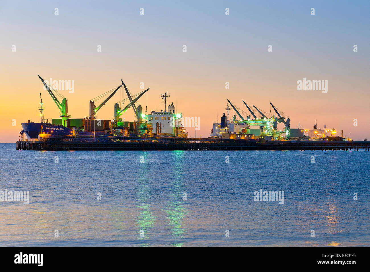 Ocean going containers ships load freight at wharf in the evening. Kwinana Industrial Estate, Rockingham Western Australia Stock Photo