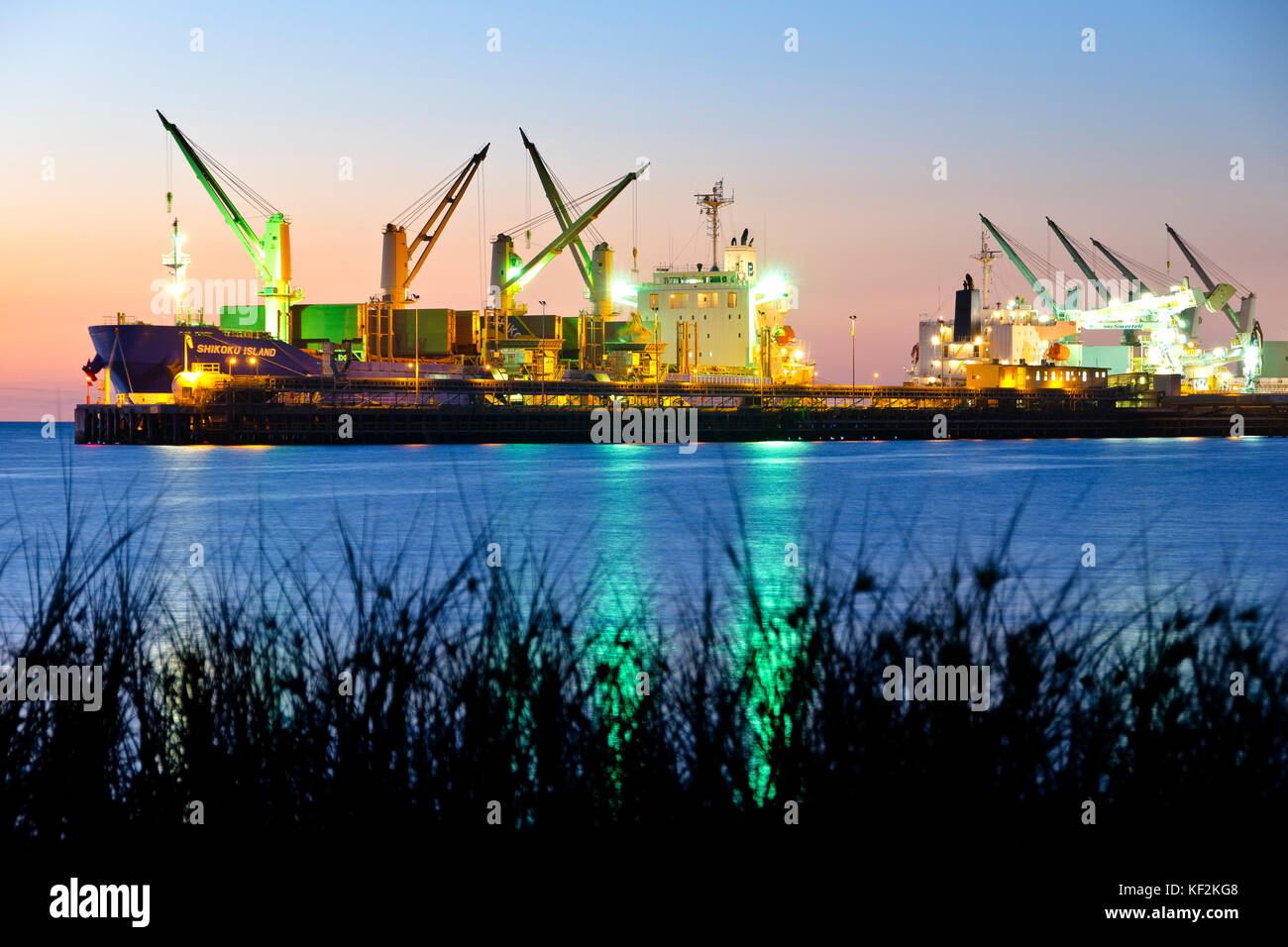 Ocean going containers ships load freight at wharf in the evening. Kwinana Industrial Estate, Rockingham Western Australia Stock Photo