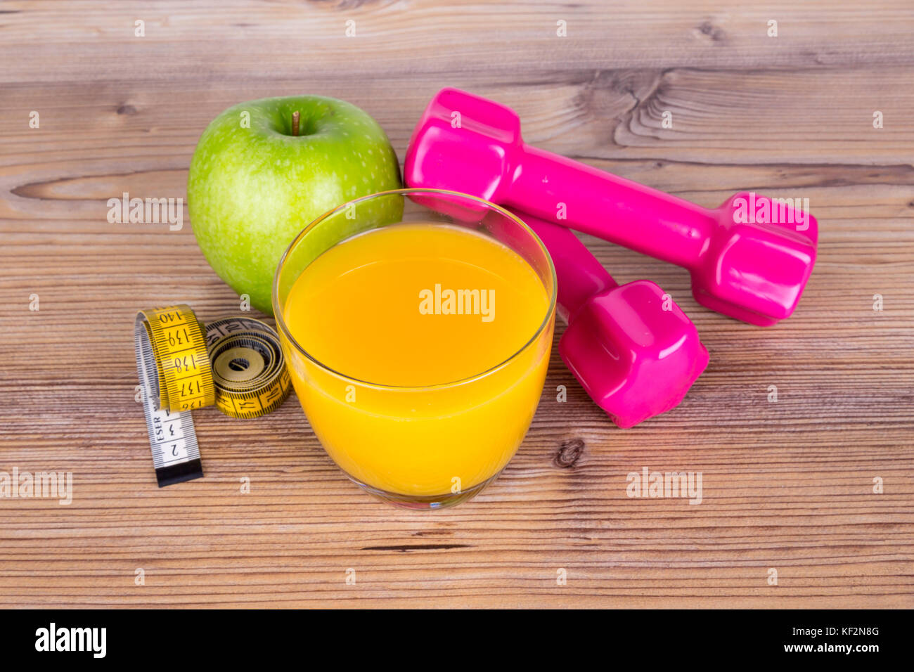 Close up top view of fruits, orange juice, light weight and green apple, measurement tape with healthy fit concept on wooden background. Stock Photo
