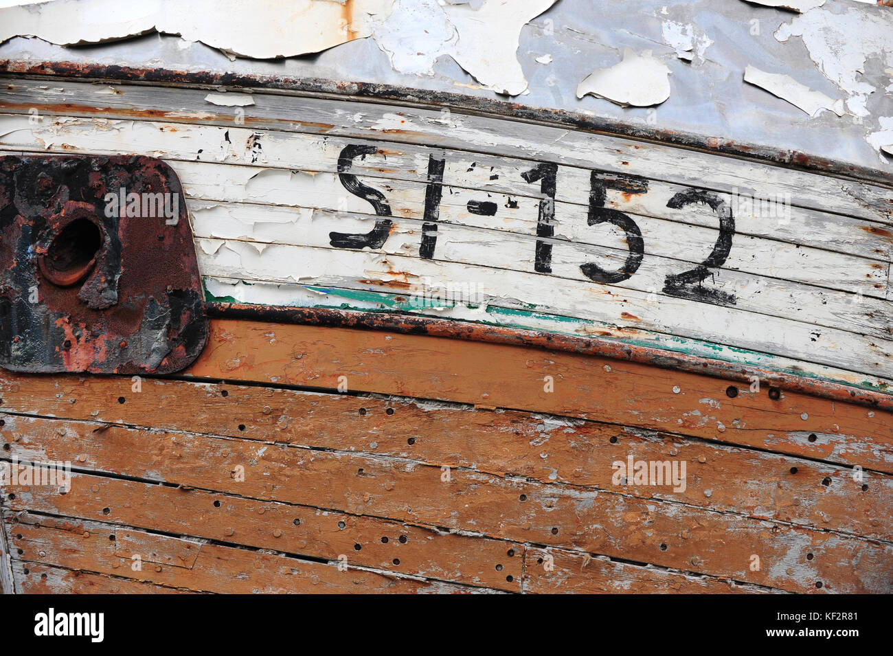 Peeled paint on weathered rusting wooden hull boards on side of boat