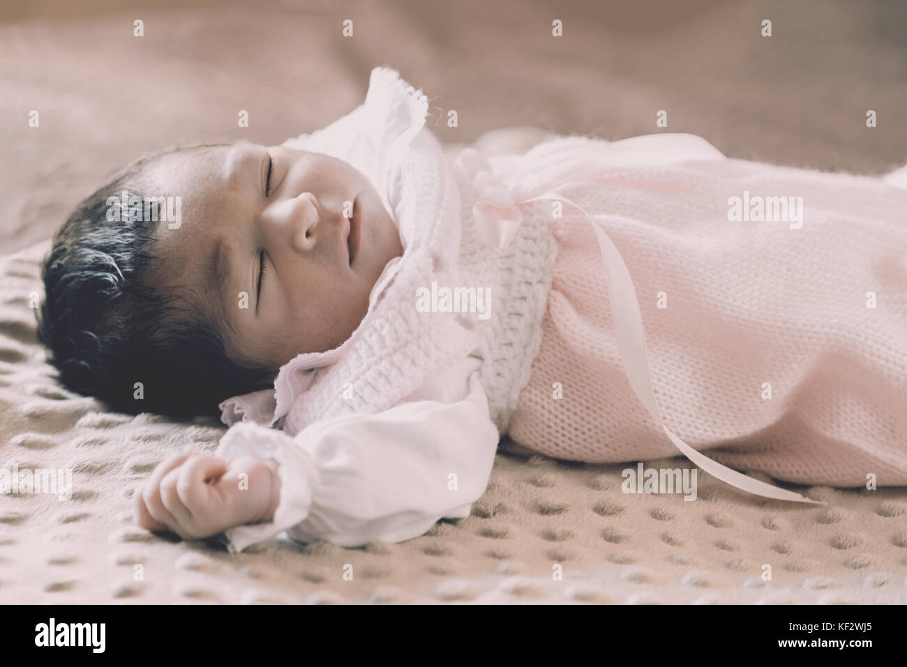 Cute two weeks old newborn baby girl wearing soft pink knit clothes