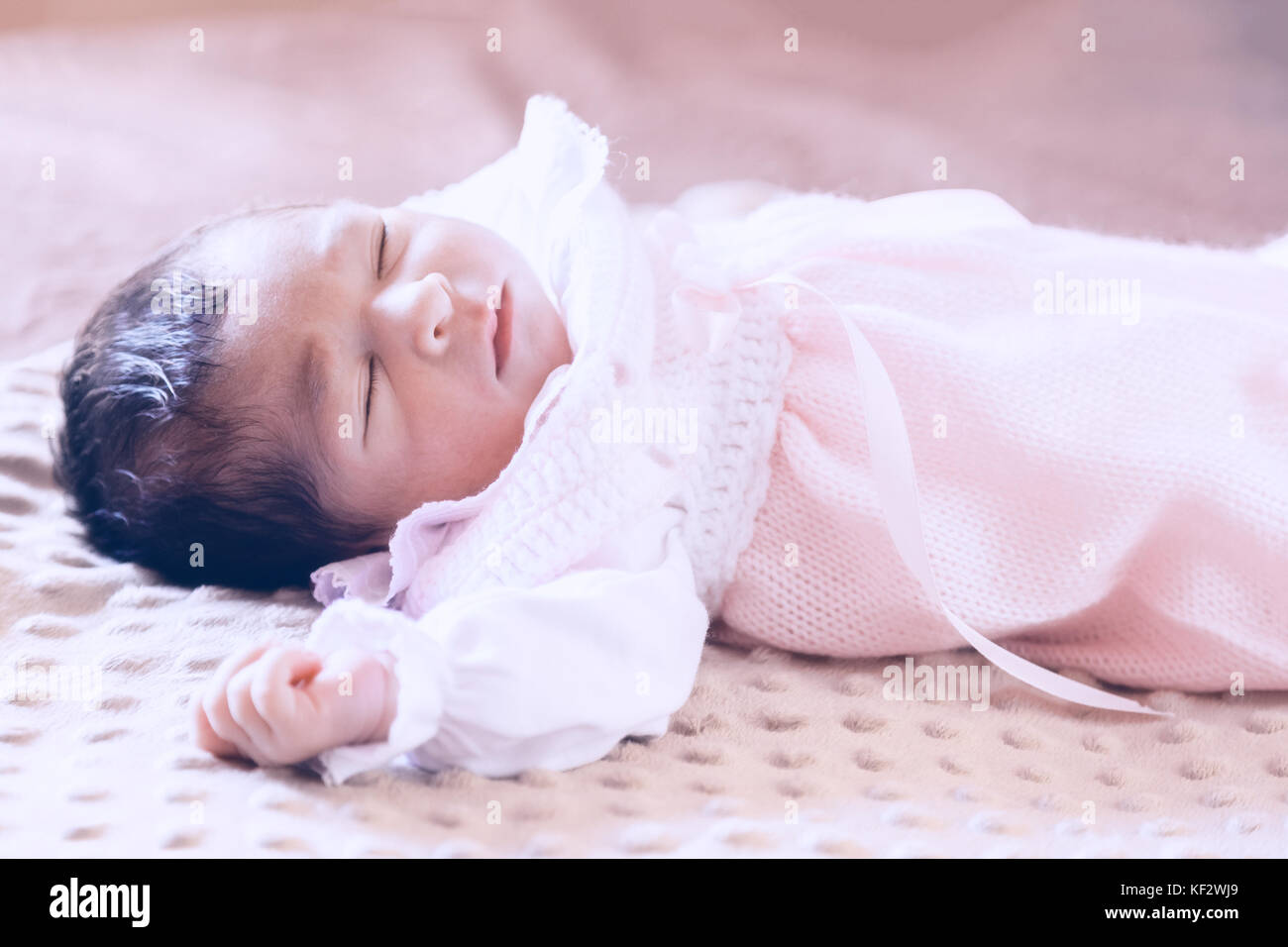 Cute two weeks old newborn baby girl wearing soft pink knit