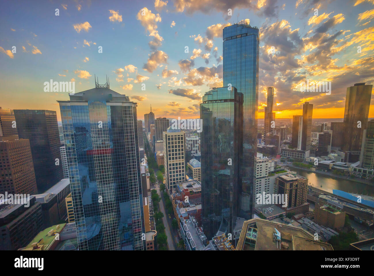 An aerial view of Melbourne cityscape including Yarra River and Victoria Harbour in the distance during sunset with beautiful sun ray bursting through Stock Photo