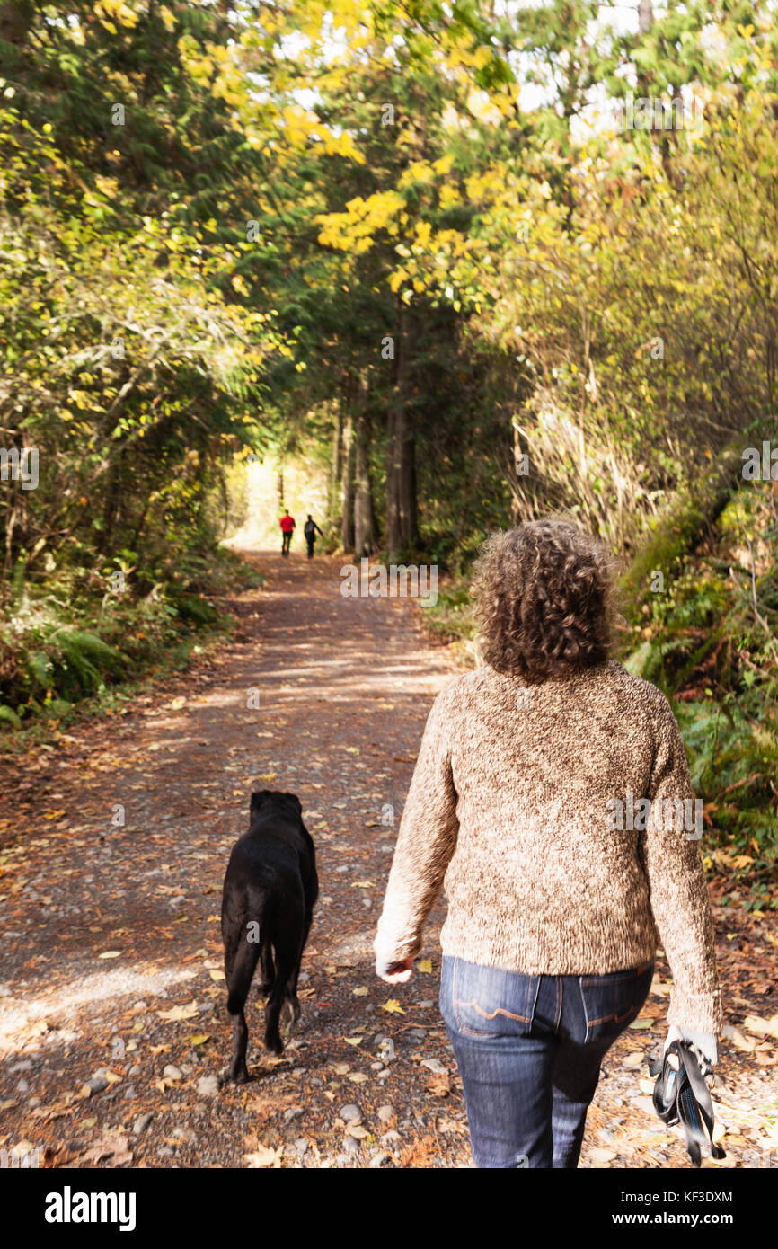 Woman walking her dog in nature. Elk Lake, Vancouver Island BC. Canada