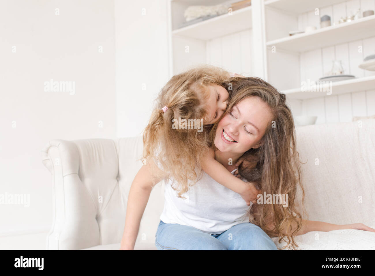 Little girl hugging her mother in the interior on a white background Stock Photo