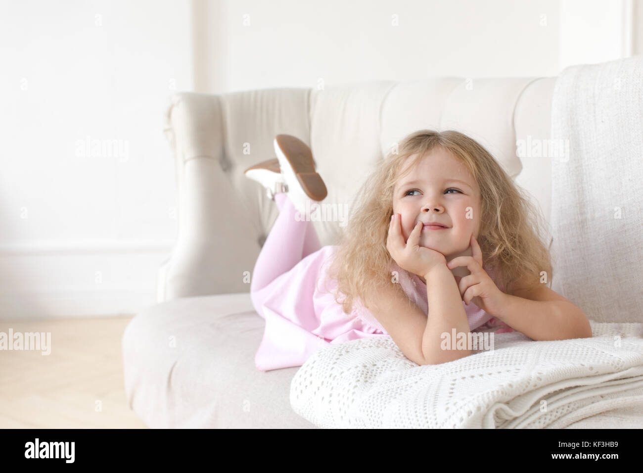 Charming little girl posing on sofa on a white background Stock Photo