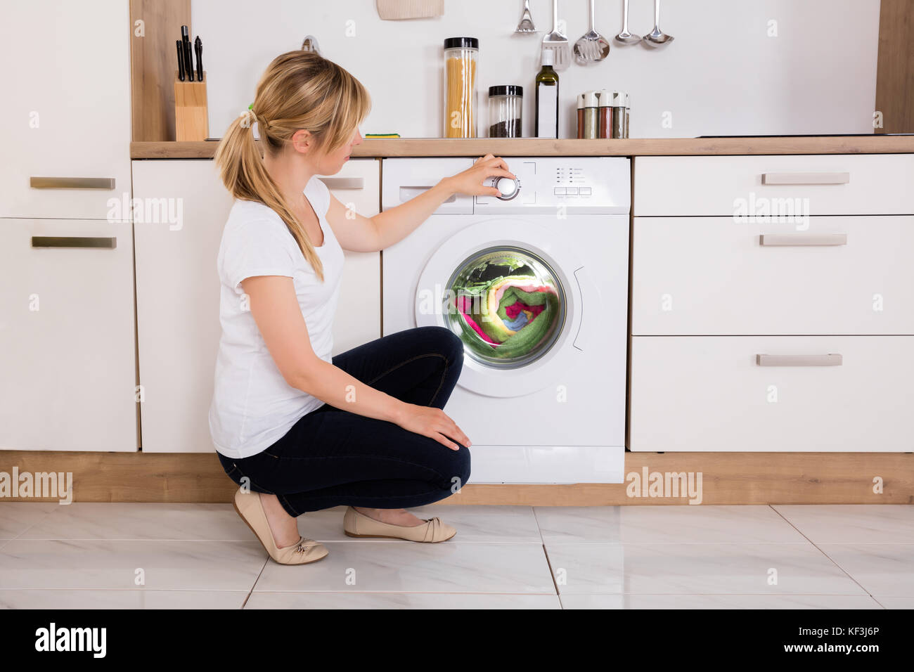 Young Woman Cleaning Multi-colored Clothes In Washing Machine At Home Stock Photo