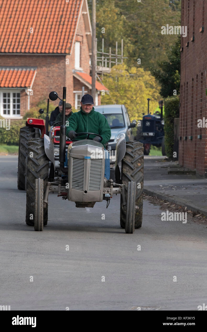 Man driving grey vintage tractor in parade through Bugthorpe village for annual charity event - Wolds Vintage Group Road Run, Yorkshire, England, UK. Stock Photo