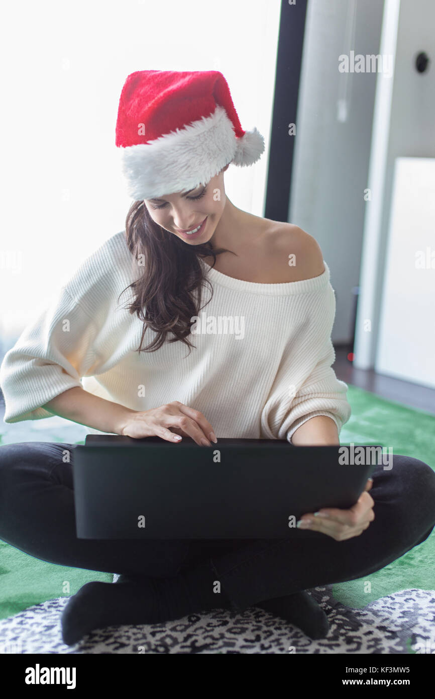 Happy young caucasian woman in santa hat shopping online for Christmas Stock Photo