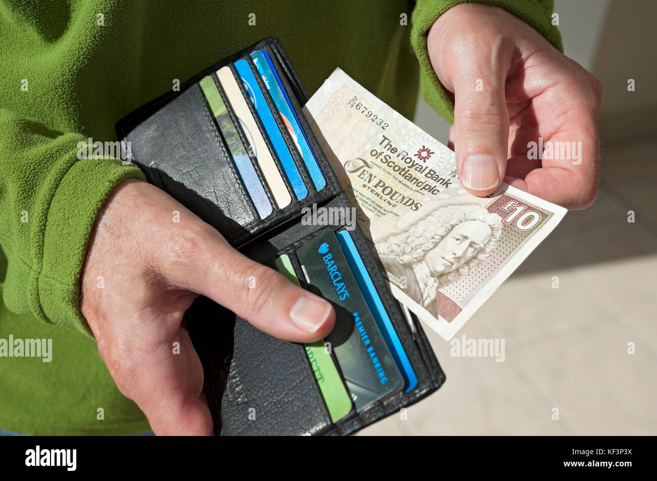 Close up of person man taking paying royal bank of Scotland Scottish £10 ten pound note money cash banknote banknotes from wallet UK United Kingdom GB Stock Photo