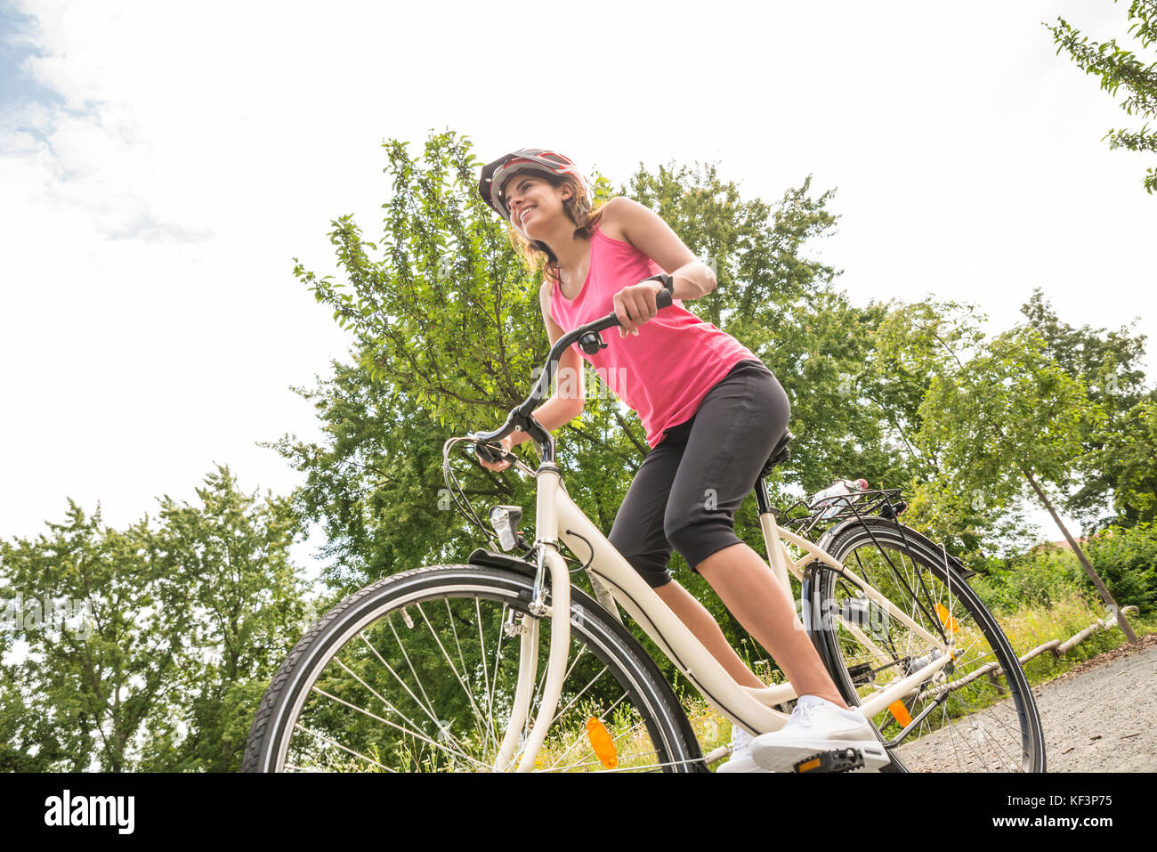 Low Angle View Of A Happy Young Female Cyclist Riding Bicycle Stock Photo