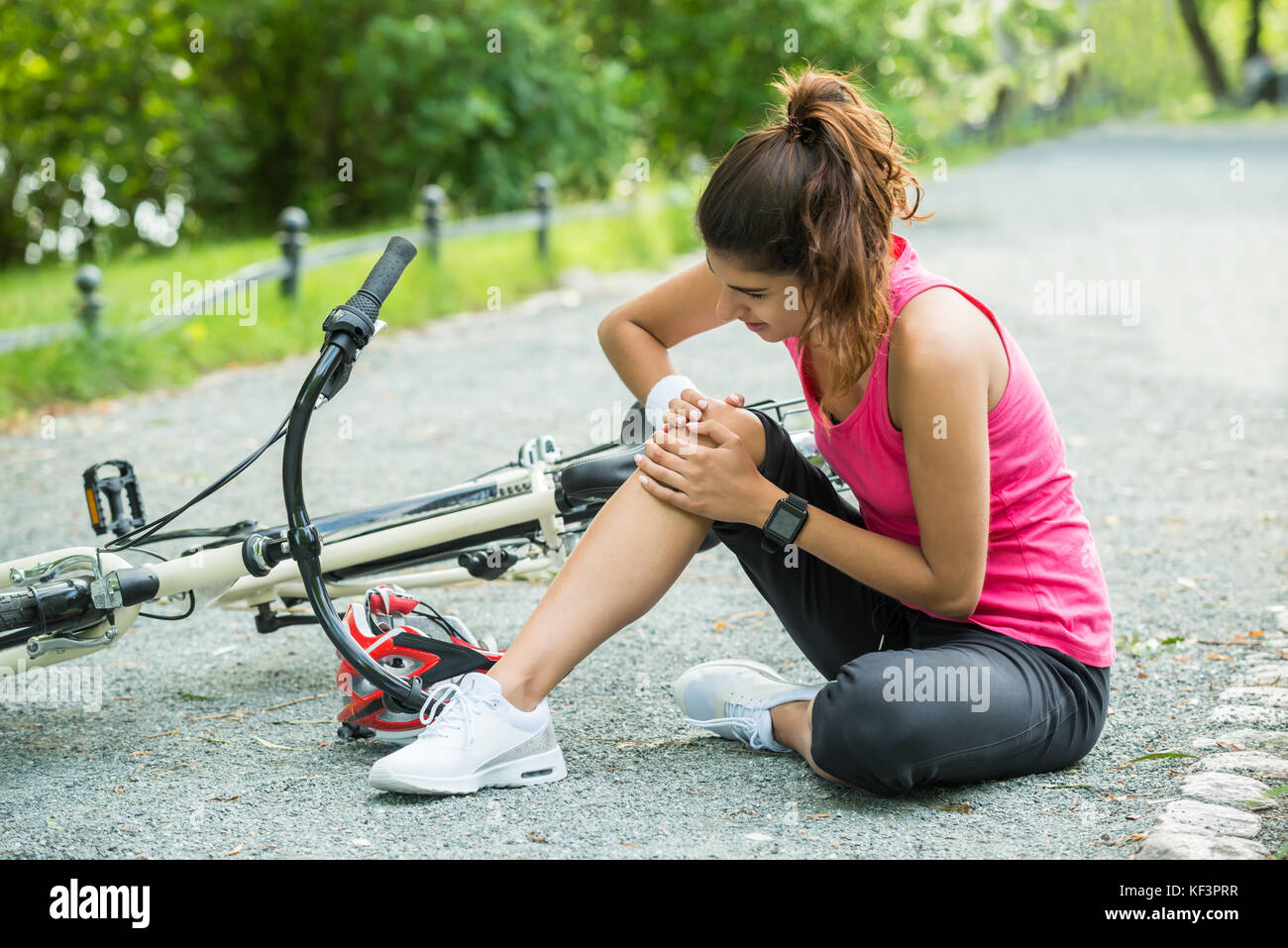 Young Woman With Pain In Knee When Fallen Down From Bicycle Stock Photo