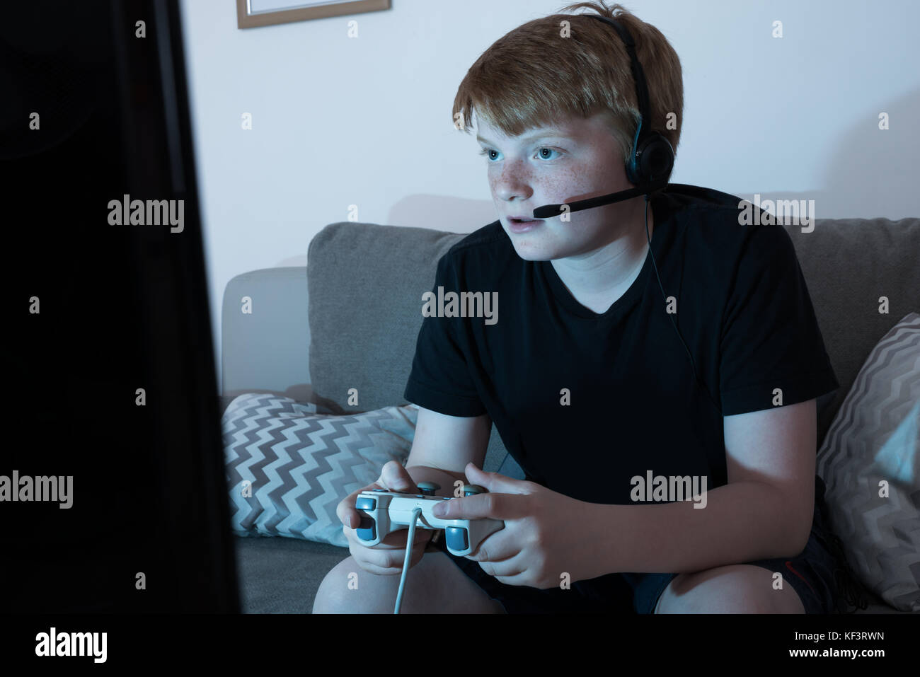 Boy With Joystick Engrossed In Playing Videogames At Home Stock Photo