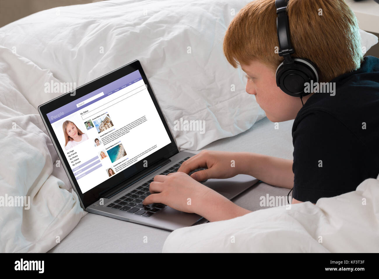 Boy Listening To Music While Chatting On Social Networking Site Using Laptop Stock Photo